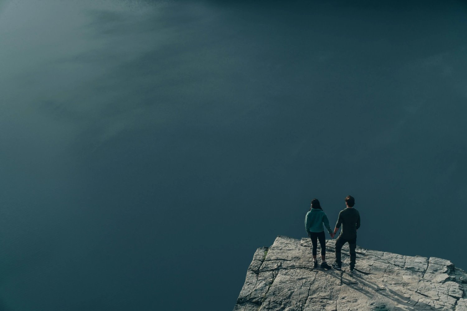 Active couple looking out over the ocean from a cliff, reflecting perspective, wellbeing and shared purpose