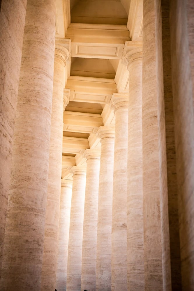 Bright stone columns curving around a walkway, reflecting structure, clarity and confident direction