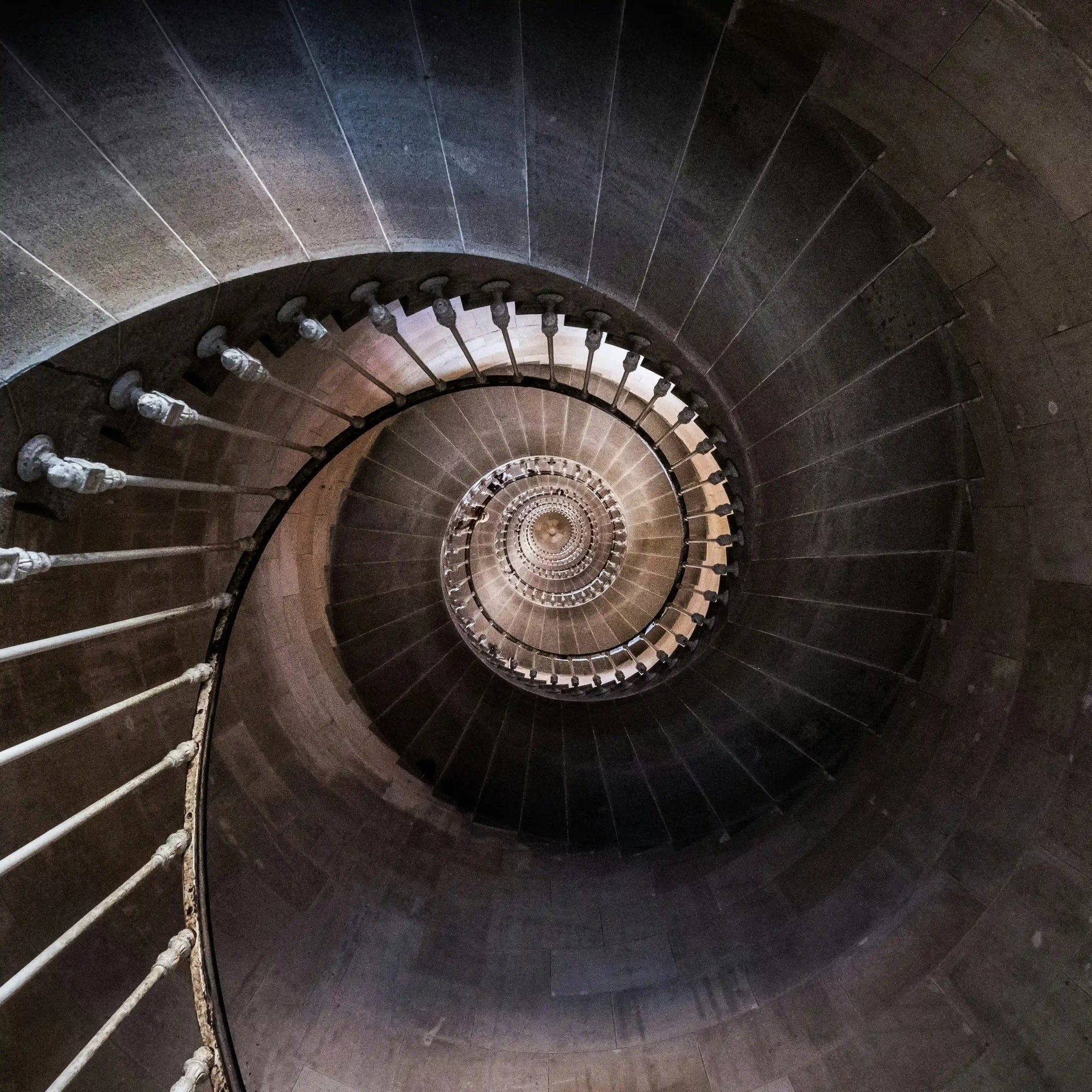 Classical stone spiral staircase viewed from below, reflecting structure, perspective and steady progress
