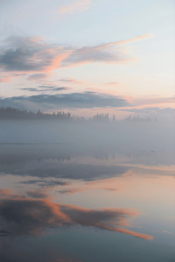 Clouds and trees reflected in a lake at sunset, reflecting calm, clarity and long-term perspective
