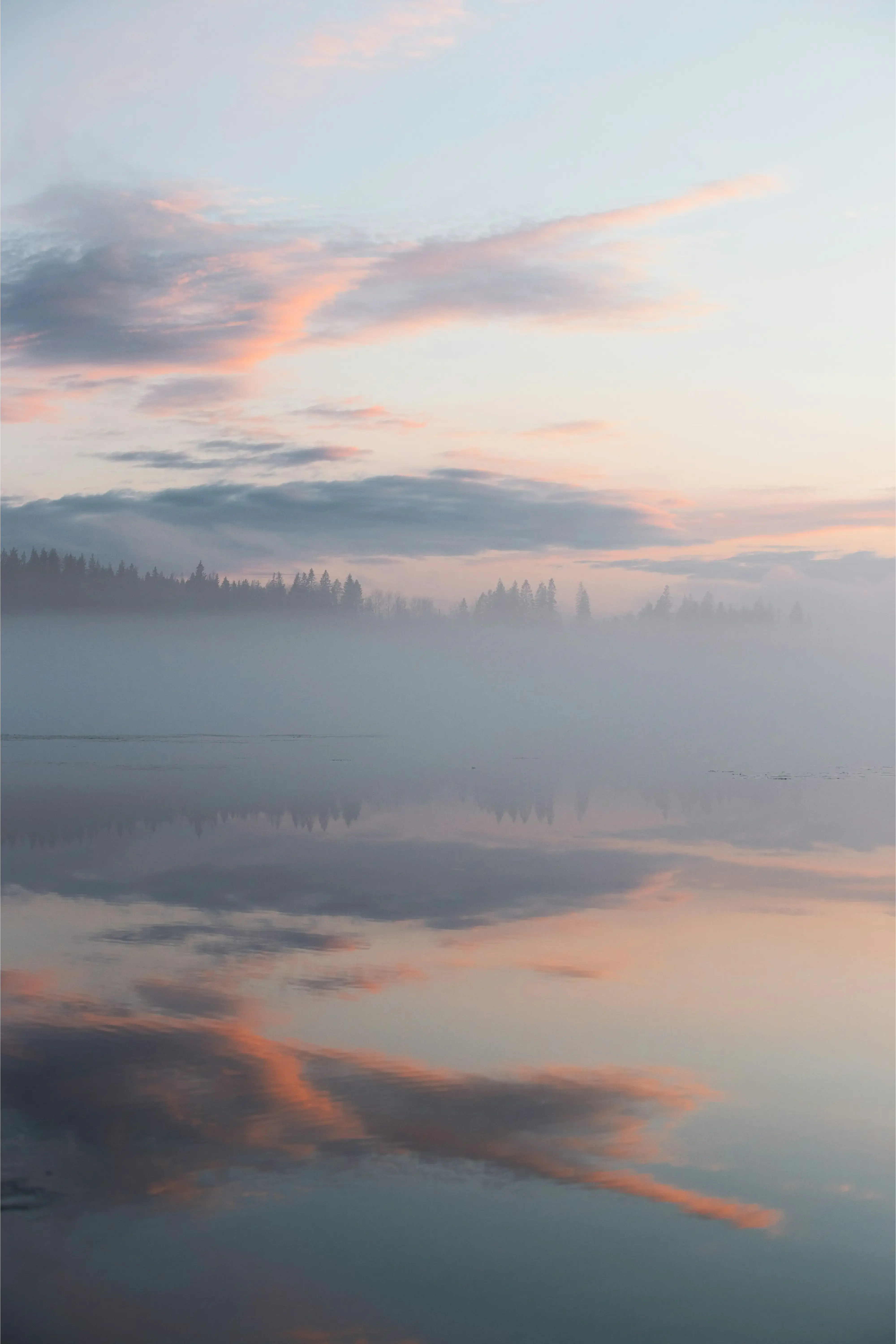 Clouds and trees reflected in a lake at sunset, reflecting calm, clarity and long-term perspective