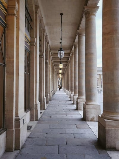 Covered stone walkway with columns in a European city, reflecting structure, heritage and confident direction