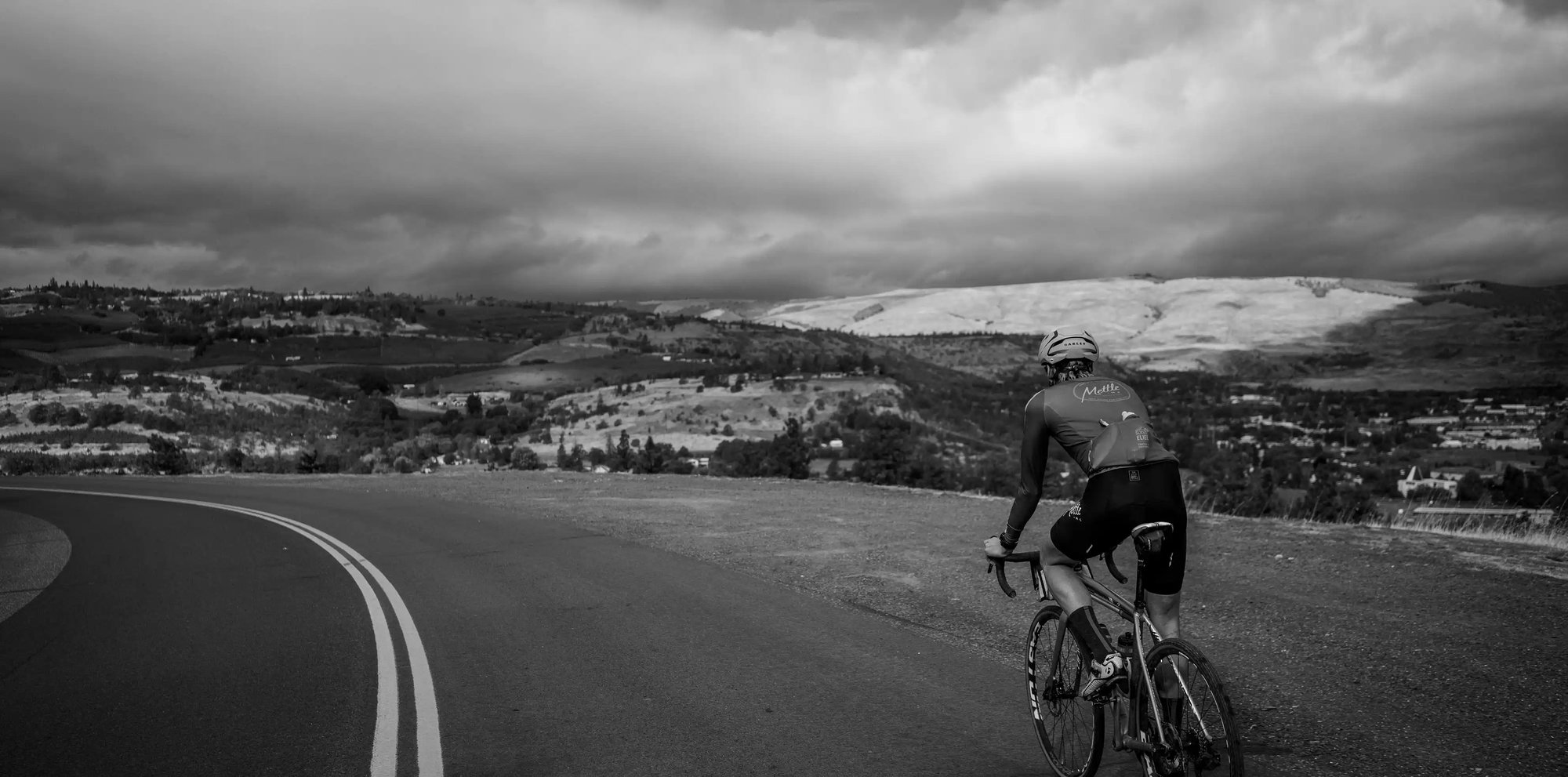 cyclist-on-mountain-road-prepares-for-descent-through-countryside
