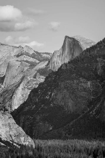 Dramatic rocky outcrop above a valley in black and white, reflecting resilience, perspective and long-term stability