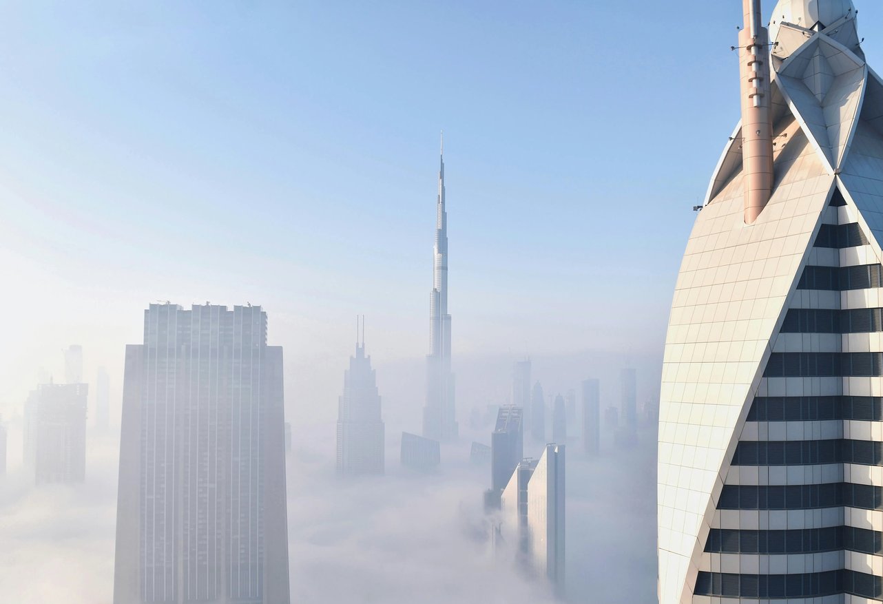 Modern Dubai skyscrapers in mist against a blue sky, reflecting perspective, opportunity and confident direction