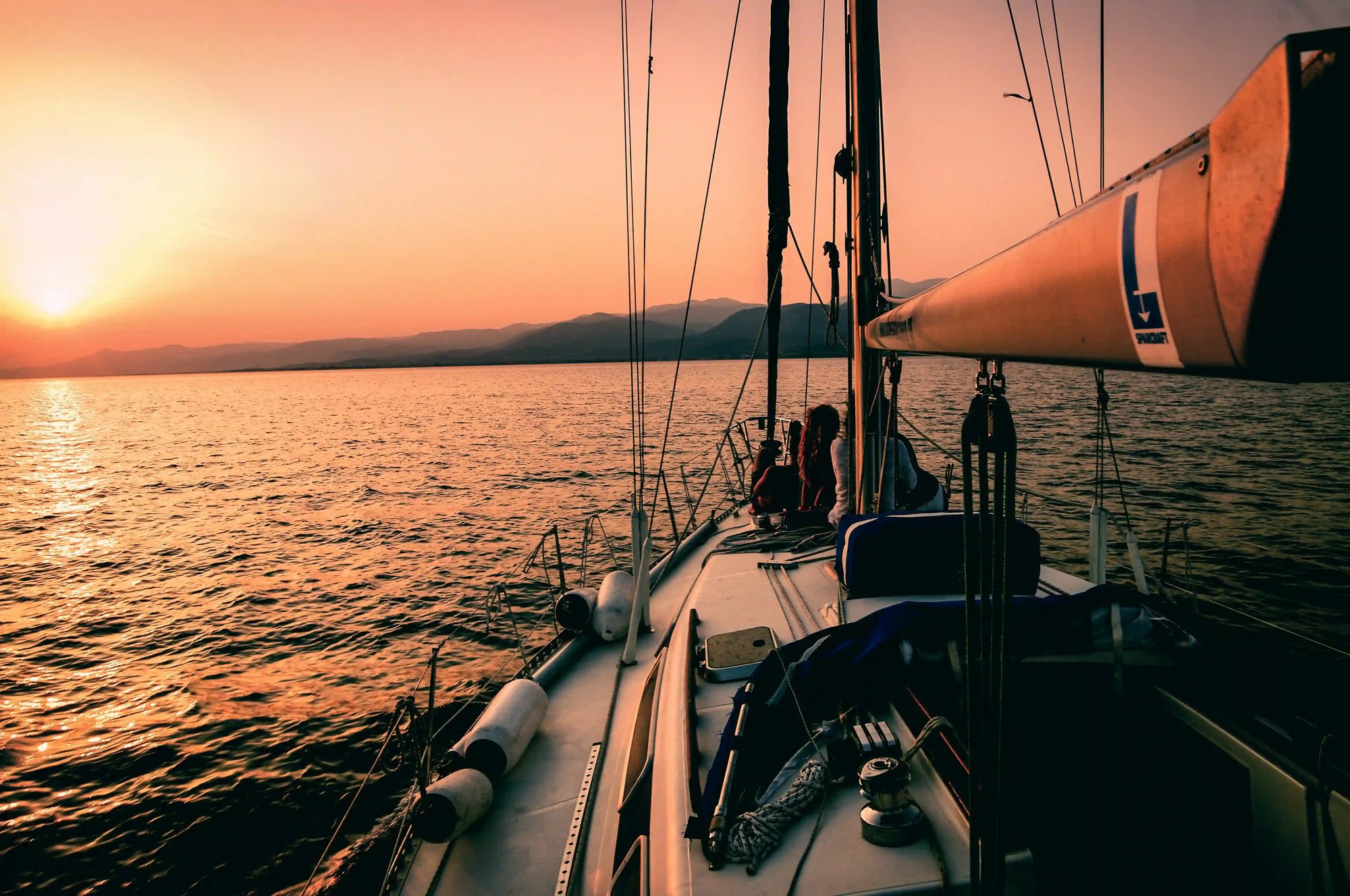 Yacht crew relaxing at sunset with rolling hills in the distance, reflecting connection, wellbeing and shared purpose