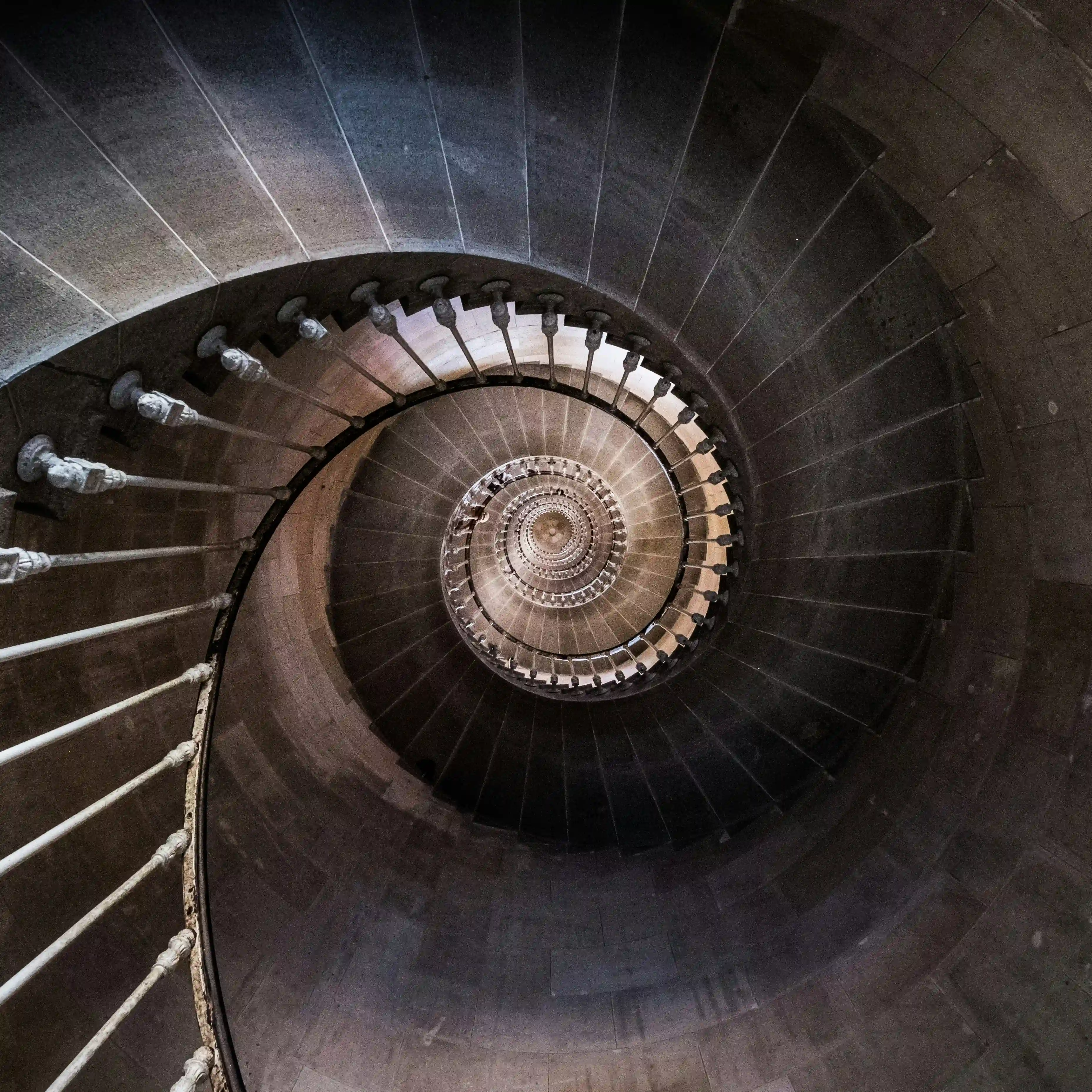 Classical stone spiral staircase viewed from below, reflecting structure, perspective and steady progress