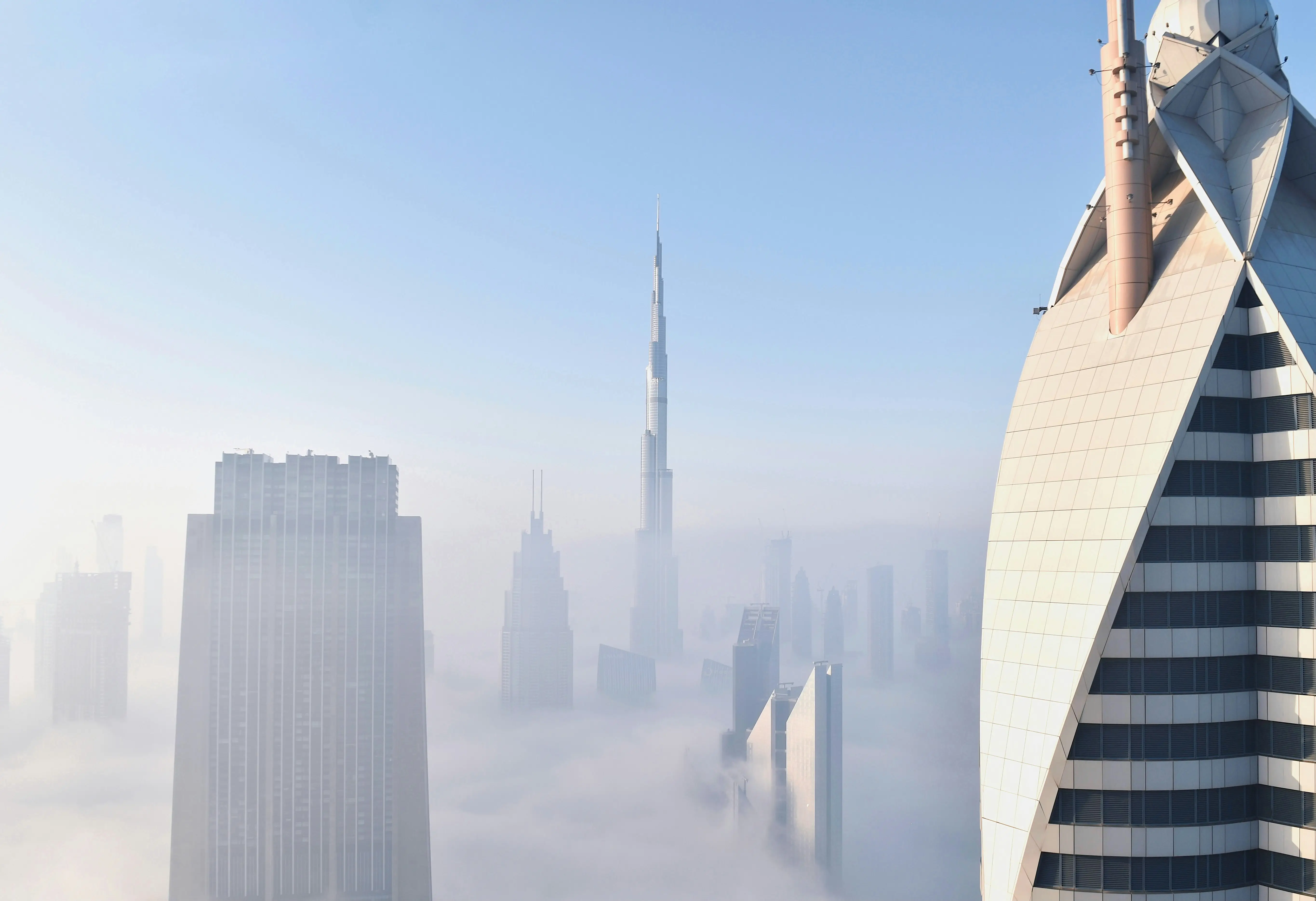 Modern Dubai skyscrapers in mist against a blue sky, reflecting perspective, opportunity and confident direction